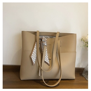 Macro detail of khaki tote bag with textured grain leather and silk scarf handle decor