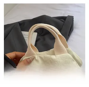 Detail of the woven handle and durable stitching on this white nylon crossbody chest bag