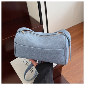 Detail of light blue denim crossbody bag with adjustable strap and silver metal zipper