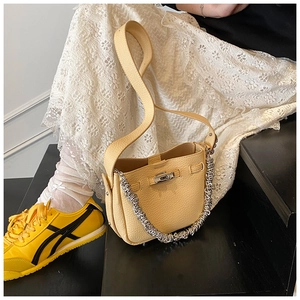 Dettaglio della borsa a secchiello giallo chiaro con catena argento e pelle martellata