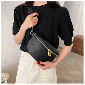 Detail of black lychee grain chest bag with gold dual zippers and wide nylon strap