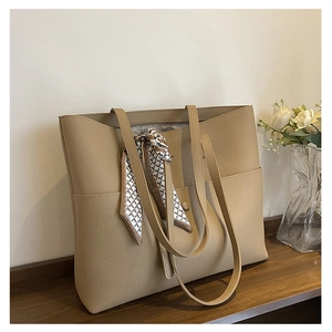 Detailed close-up of khaki leather tote bag showing lychee grain and decorative scarf
