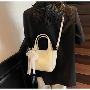 Detail of cream lychee leather bucket bag with lace pearl bow and shoulder strap