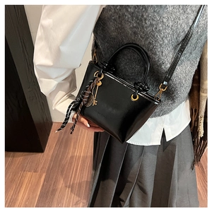 Détail d'un mini sac seau noir brillant avec foulard en soie et breloques de raquette de tennis