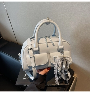 Close-up of light blue Boston handbag with dual front flap pockets and pearl charm
