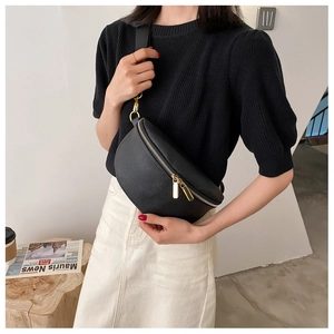 Detail of black lychee grain leather crossbody bag with elegant gold zipper and hardware