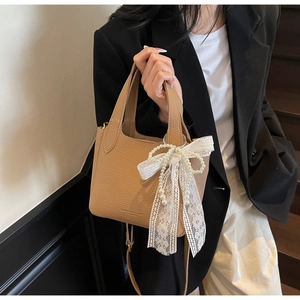 Close-up of light brown litchi leather bag with pearl lace bow charm detail
