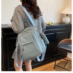 Detail of light blue textured leather backpack with patterned strap worn by a model
