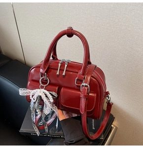 Detail of red patent leather Boston bag with silver hardware and plaid bow charm