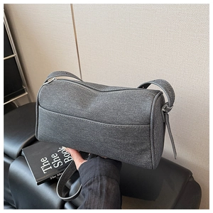 Close-up of a grey denim cylinder bag showing high-quality fabric texture and zipper