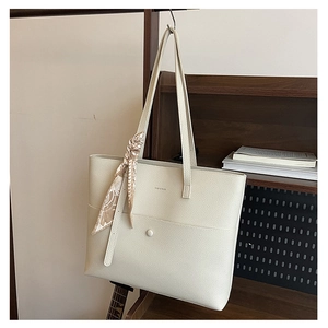 Detail view of cream tote bag with lychee texture leather and floral scarf accent