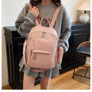 Detail of light pink pebble grain backpack with multi-layer zipper and side mini pouch