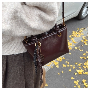 Détail du mini sac cabas en cuir marron rougeâtre foncé avec poignées nouées et anneau doré
