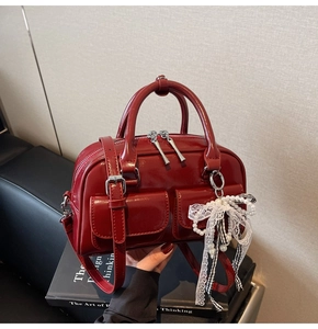 Detail of red patent leather Boston bag with decorative bow and double front pockets
