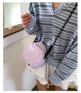 Detailed shot of a lavender shell-shaped crossbody bag with striped textured strap