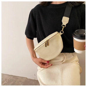 Detailed shot of beige lychee texture crescent chest bag with gold zipper and wide strap