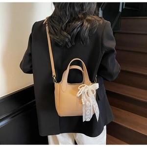 Detailed view of apricot litchi leather bucket bag with lace bow and pearl charm