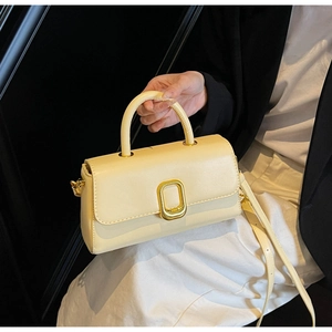 Détail d'un sac à main minimaliste en cuir crème avec boucle en métal doré texturé