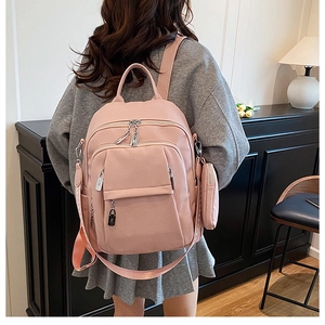 Detailed back view of pink leather backpack featuring multiple zippers and side pouch