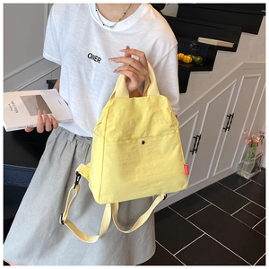 Close-up of a versatile yellow canvas chest bag held by a model in a modern home interior