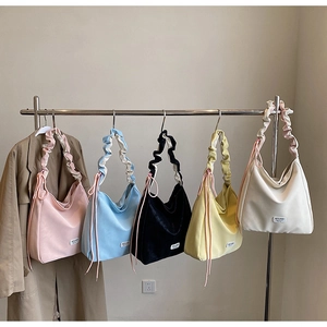 Multiple colors of large tote bags with ruched handles and side drawstrings hanging