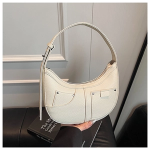 Detail der cremeweißen Tasche mit Lychee-Struktur und verstellbarem silbernem Gurt