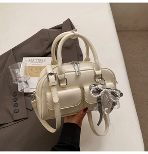 Detail of cream Boston bag with pearl lace bow charm and front flap pockets