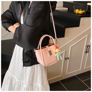 Detail of pink bucket bag with matte leather finish, silver buckle and cartoon charm