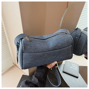 Detail of blue denim square bag showing metal zipper closure and high-quality twill texture
