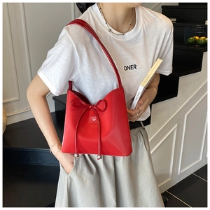 Détail d'un sac seau en cuir rouge avec cordon à nœud et charms métalliques sur un mannequin