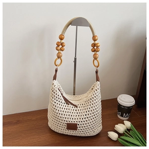 Détail du sac seau ajouré tissé main avec poignée en perles de bois et logo en cuir