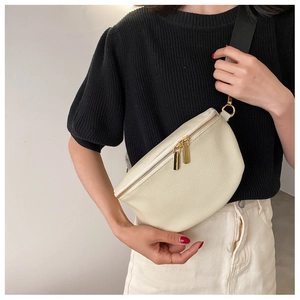 Detailed view of cream leather waist bag with pebbled texture and gold metal hardware