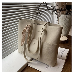Close-up of beige tote bag with litchi grain leather texture and silk scarf detail