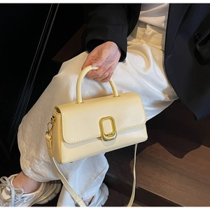 Détail d'un sac à main beige crème en cuir PU avec fermoir doré tenu par un mannequin
