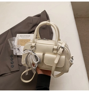 Elegant cream Boston bag with pearl lace charm and dual front pockets detail
