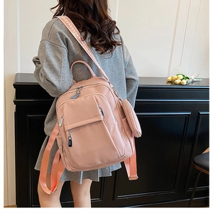 Pink faux leather backpack showing detailed pebble texture and circular charm pendant