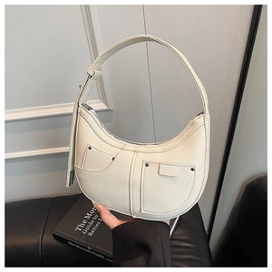 Close-up of cream crescent bag featuring lychee texture and metallic rivet detailing