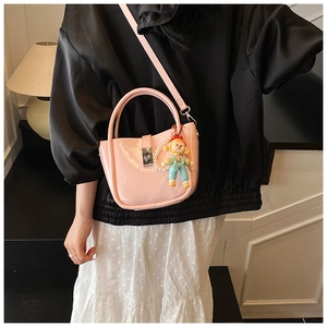 Pink patent leather bucket bag with pearl chain and doll charm shown on model