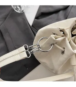 Detailed shot of white drawstring bucket bag featuring polished silver metal hardware