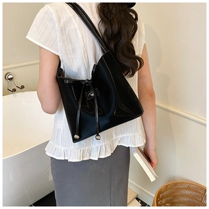Détail d'un sac seau en cuir verni noir avec cordon de serrage et longues brides