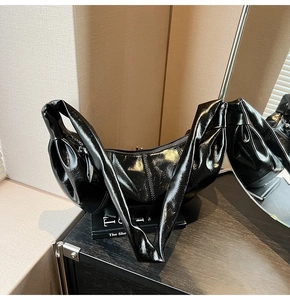 Detail of glossy black crescent shoulder bag featuring reflective faux leather finish
