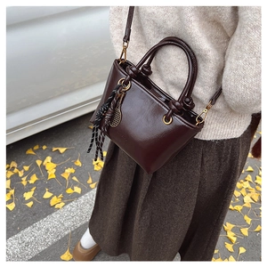 Détail du sac en cuir marron foncé brillant avec pendentif raquette et cordon tressé