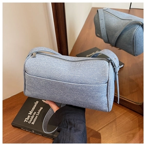 Detail view of light blue denim fabric texture and metal zipper on the shoulder bag