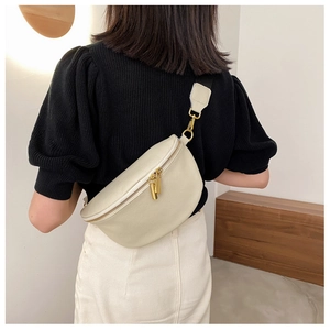 Detailed view of cream lychee leather chest bag with golden zippers worn by a model