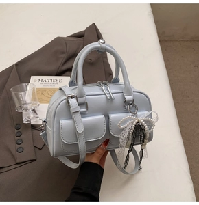 Detail of light blue leather Boston bag with side pearl lace charm and front pockets