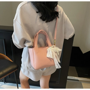 Detailed back view of a pink leather bucket bag with lace bow and pearl charm worn crossbody