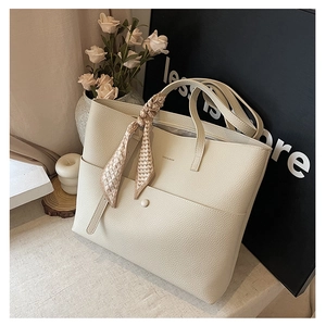 Close-up of cream tote bag featuring lychee texture and decorative floral silk scarf