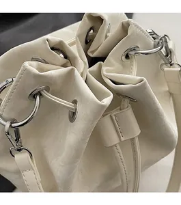 Detail of white drawstring bucket bag showing silver metal eyelets and leather texture