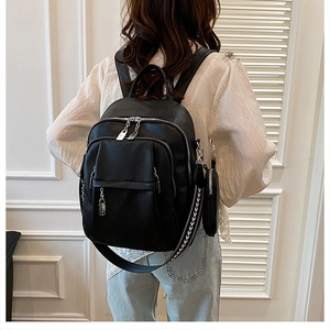 Close-up of black leather backpack with ethnic woven strap and mini round pouch charm