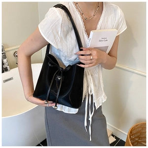 Détail du sac à bandoulière en cuir verni noir brillant avec nœud et perles métalliques